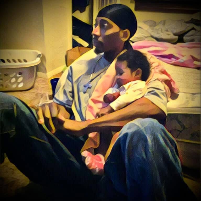 Painterly photograph of Jerome cradling a sleeping baby